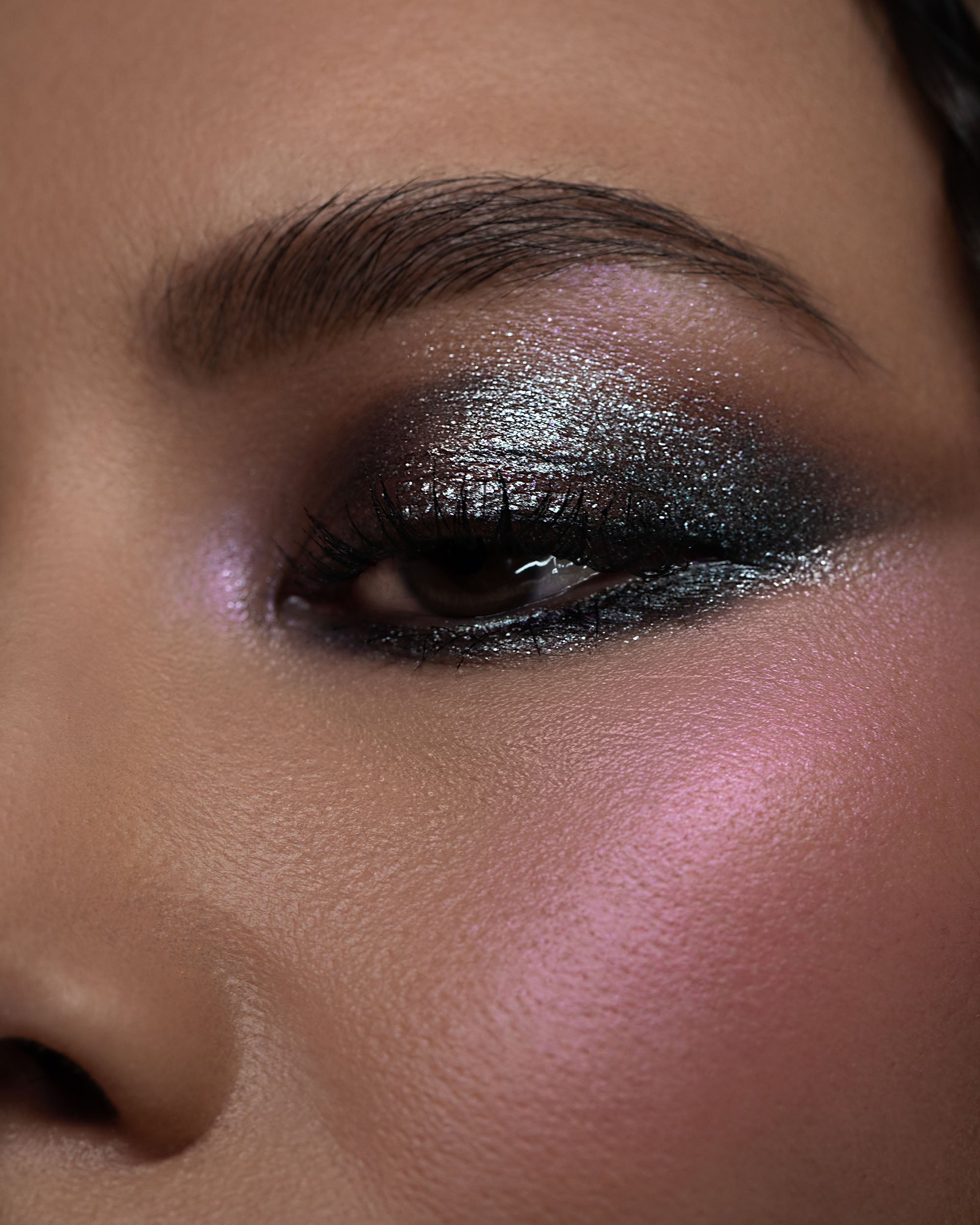 Close-up of a person's eye with dark smoky eye makeup and pink blush.