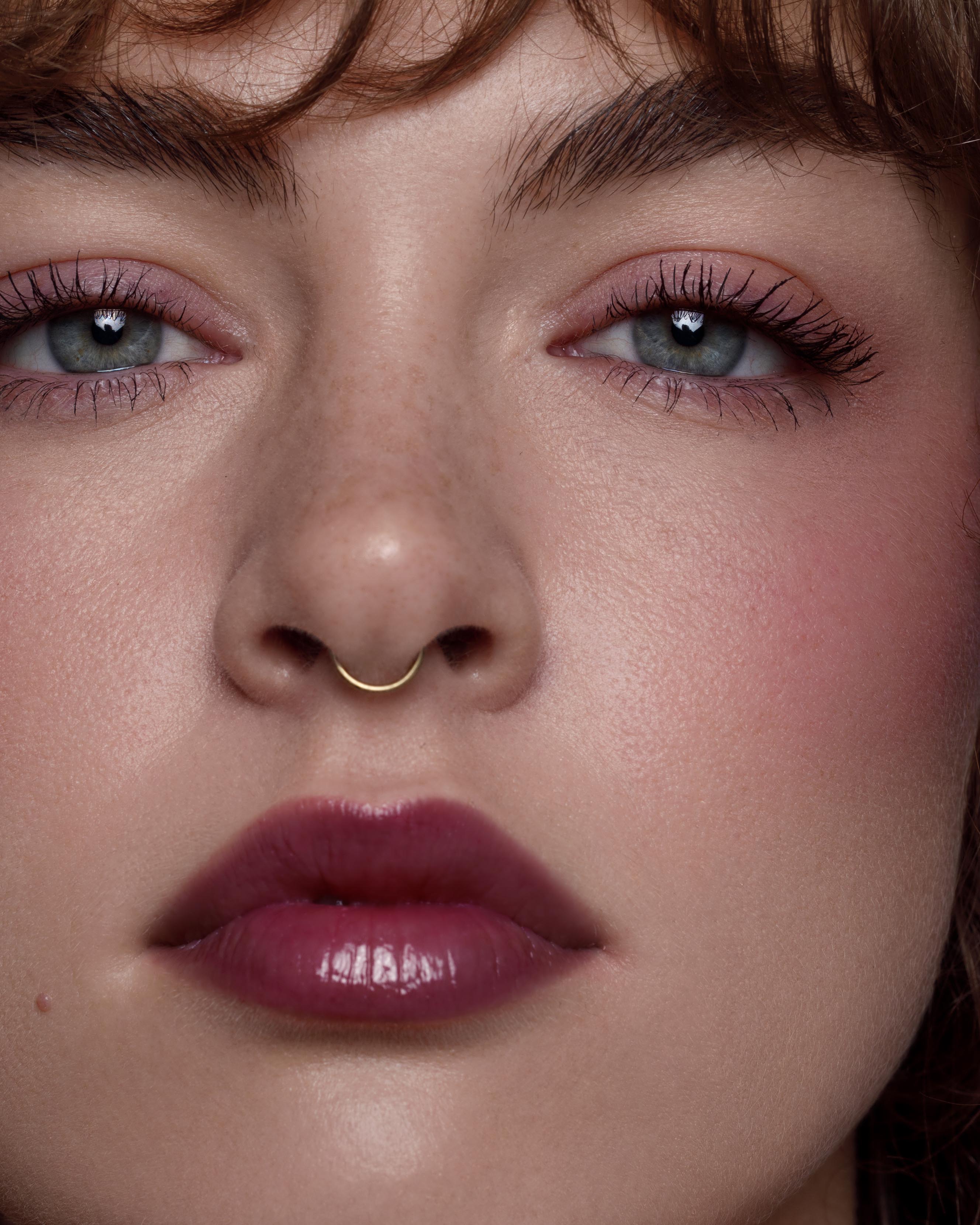 Close-up of a model with light skin wearing purple makeup on lips, eyes, and cheeks