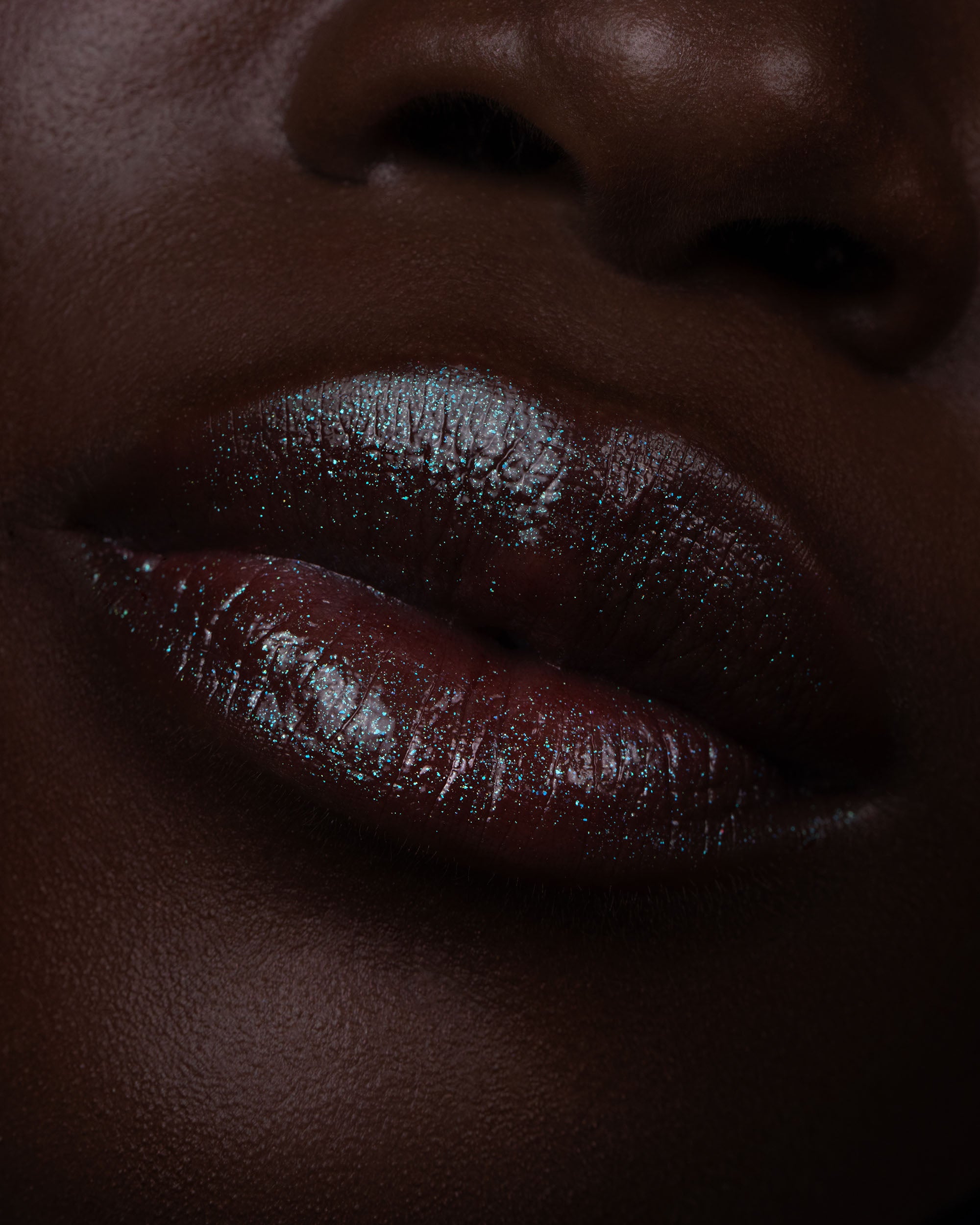 Close-up of dark red lip gloss on deep skin