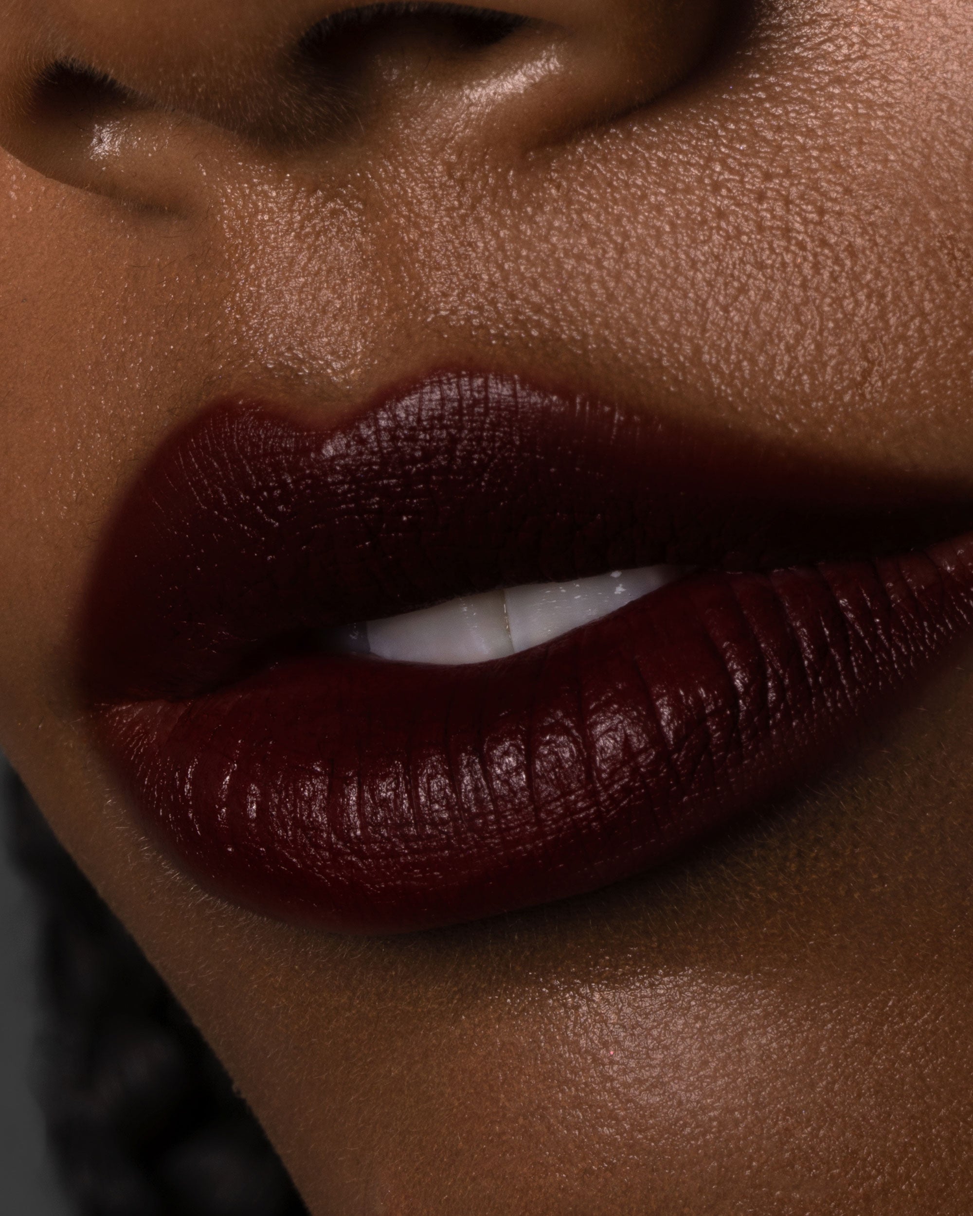 Close-up of a person wearing dark red lipstick on a blurred background