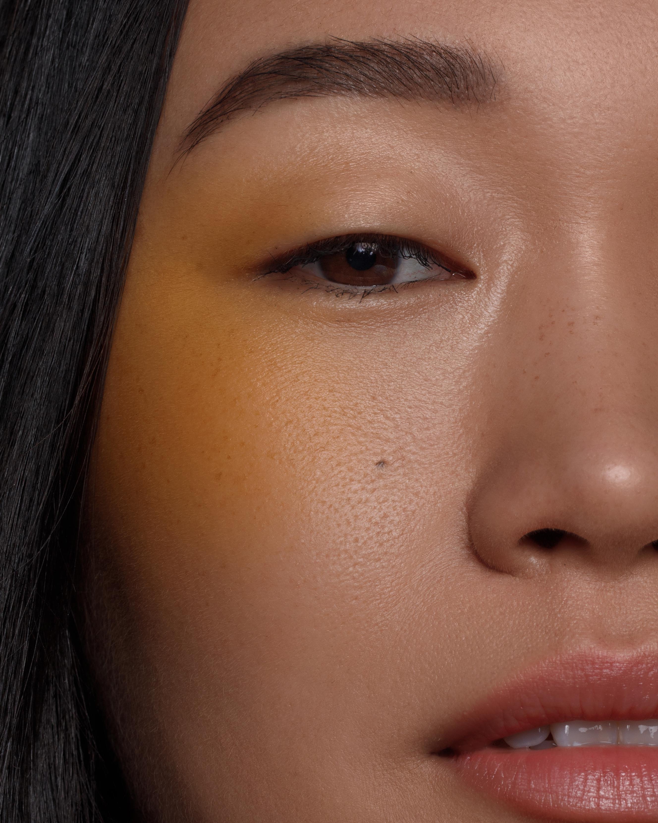 Close-up of a model with medium skin wearing bright eyllow makeup on the eyes, and cheeks