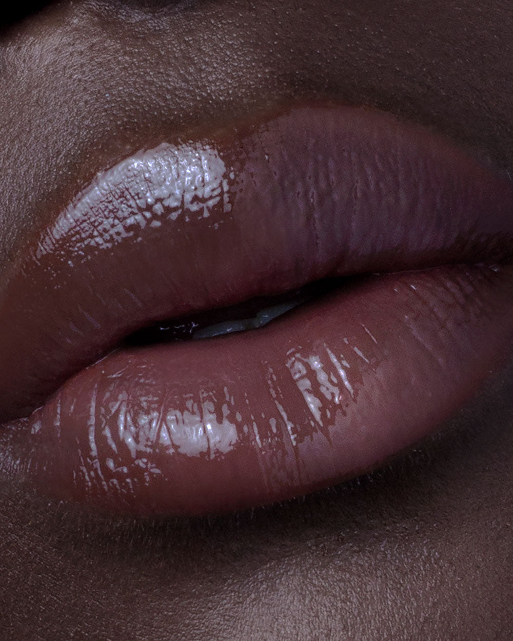 Close-up of glossy brown lipstick on a person's lips