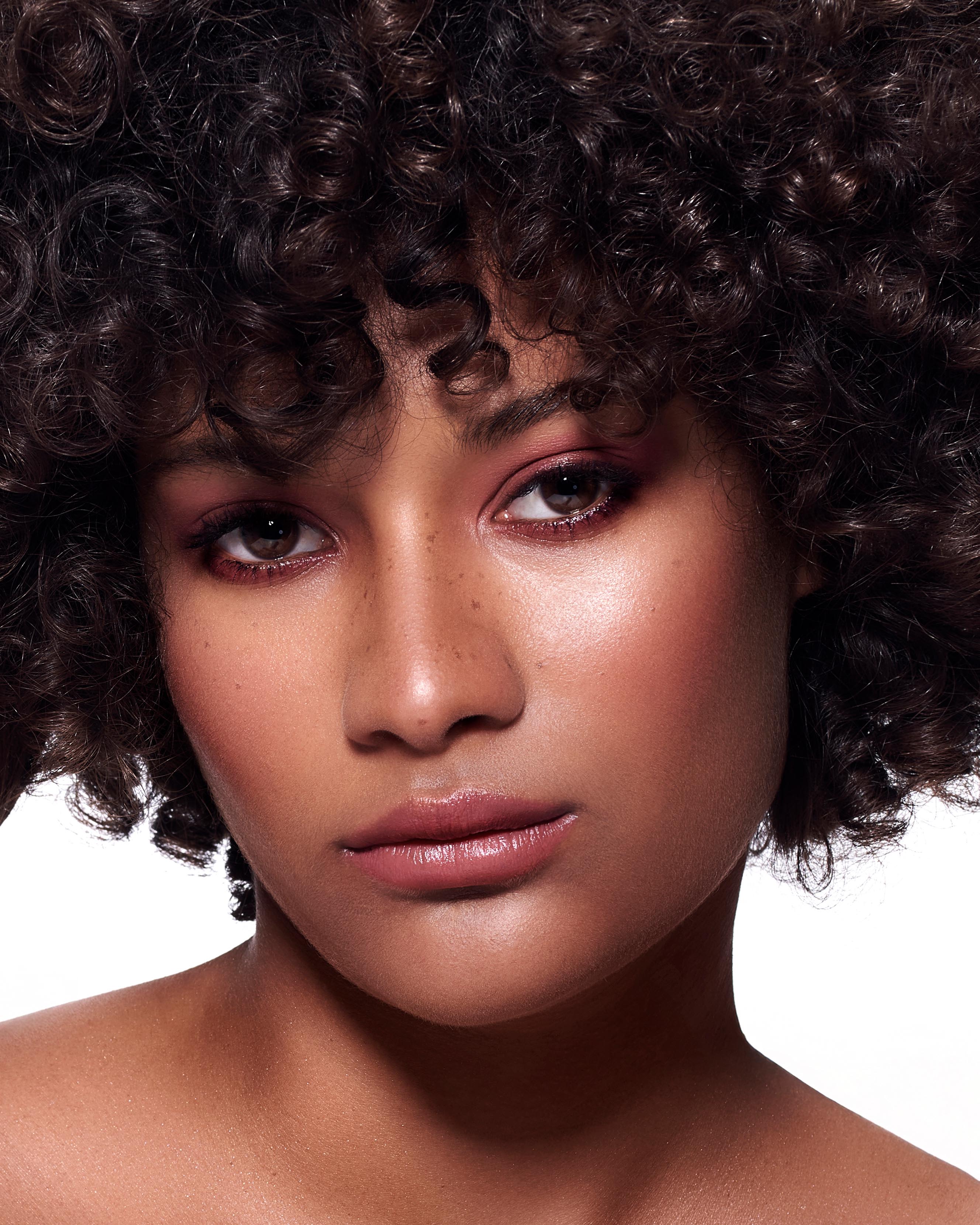 Close-up of a model with medium skin wearing pink lip and eye makeup