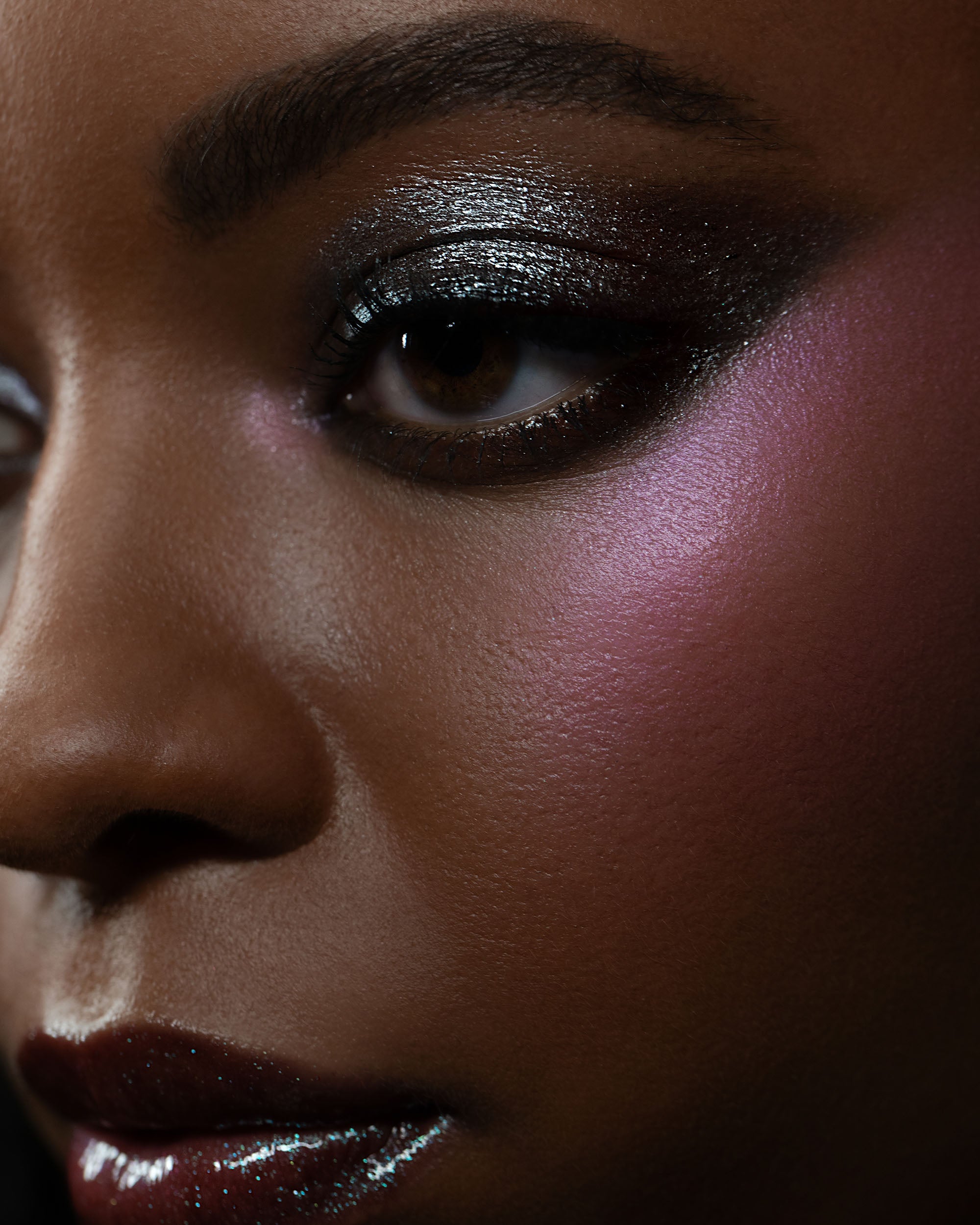 Close-up of a person's eye with dark eyeshadow and pink blush.