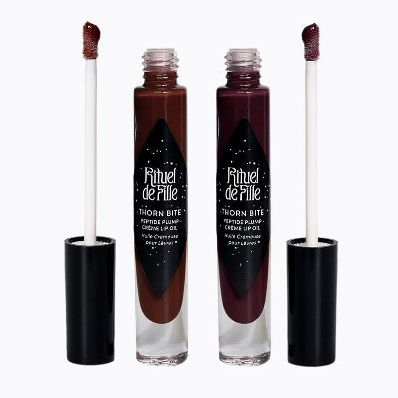 Two lip oil products with applicators on a white background, featuring the brand 'Rituel de Fille'.