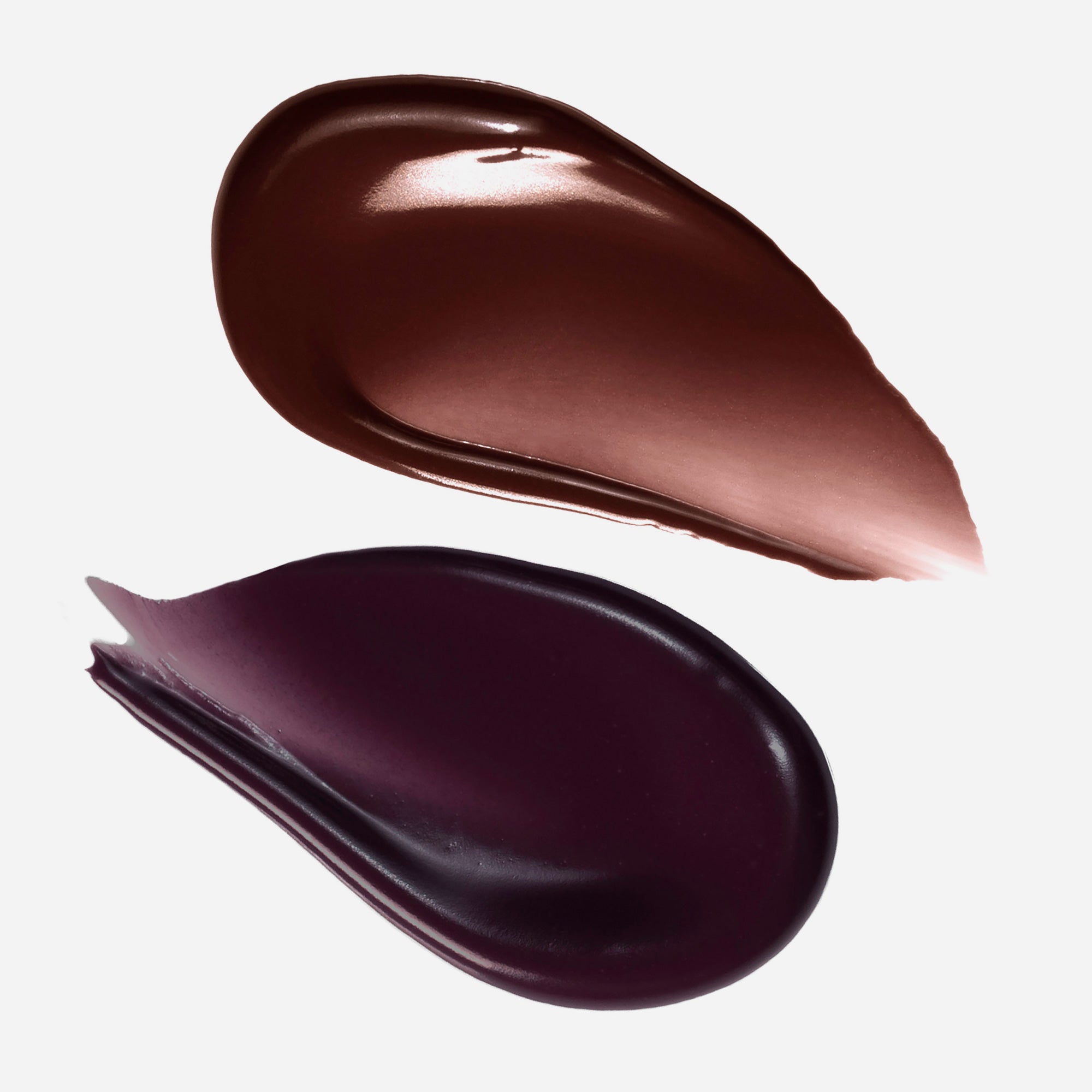 Two swatches of brown and black makeup cream on a white background