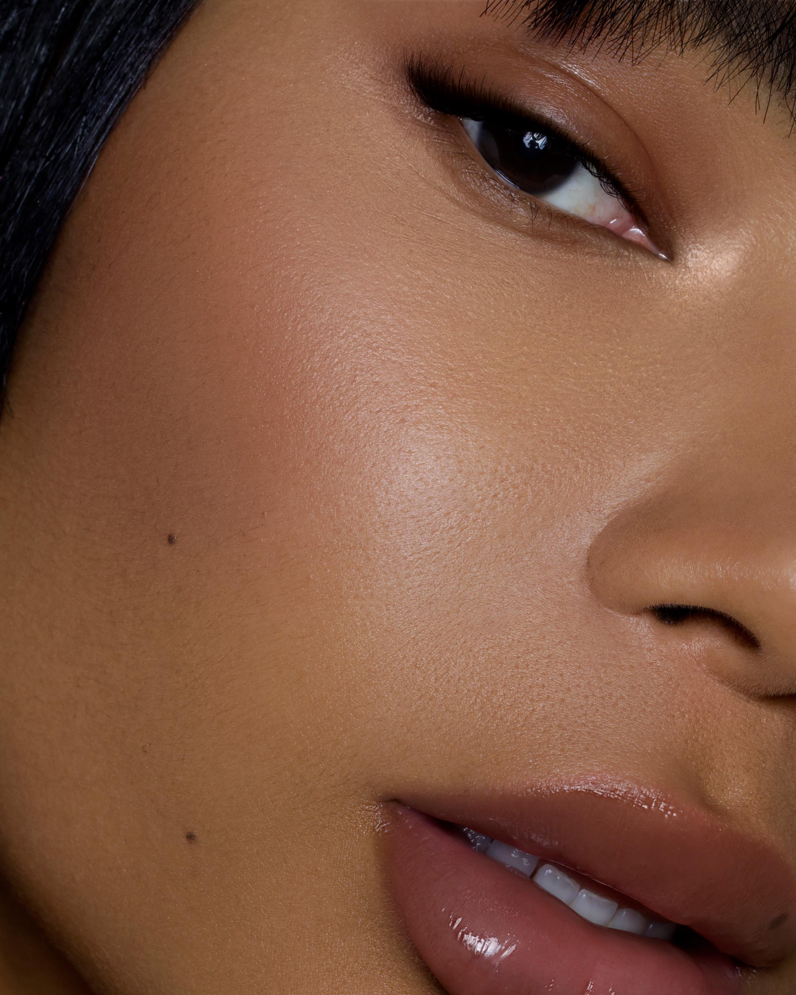 Close-up of a model with medium-deep skin wearing rose pink makeup on lips and cheeks