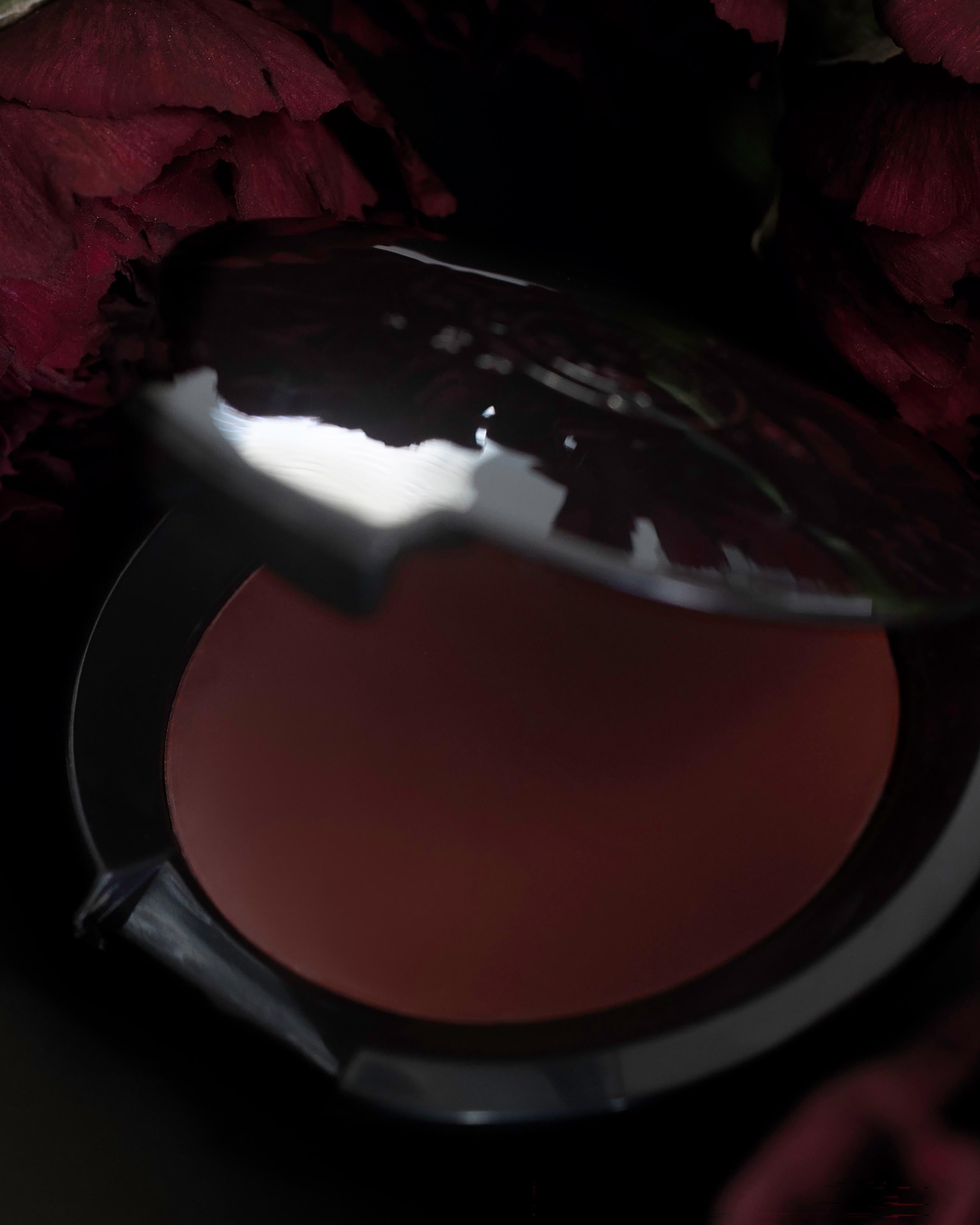 Rose pink makeup in black compact on a dark floral background
