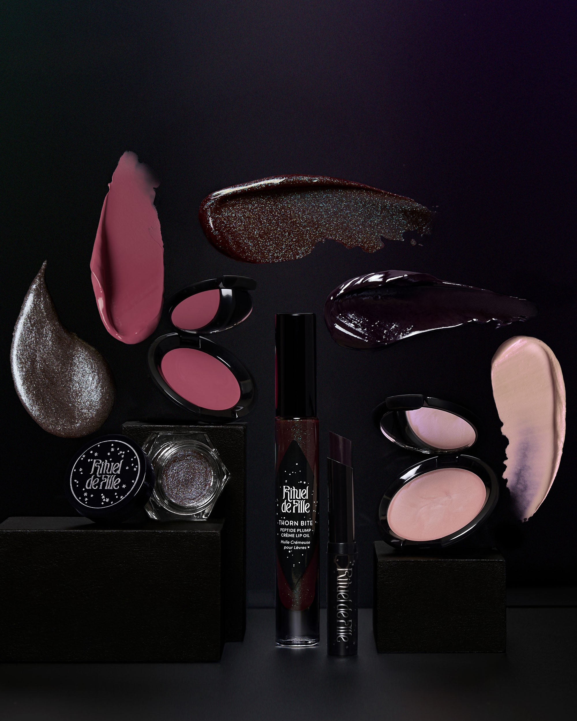 Makeup products including lipsticks, blushes, and a mascara on a dark background