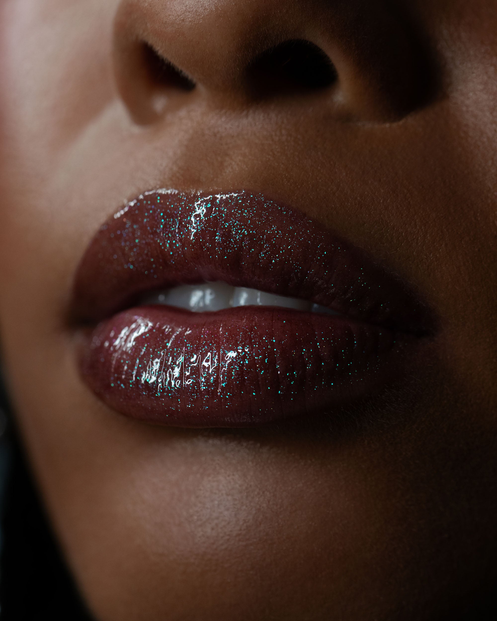 Close-up of a person's lips with glossy, dark red lip gloss.