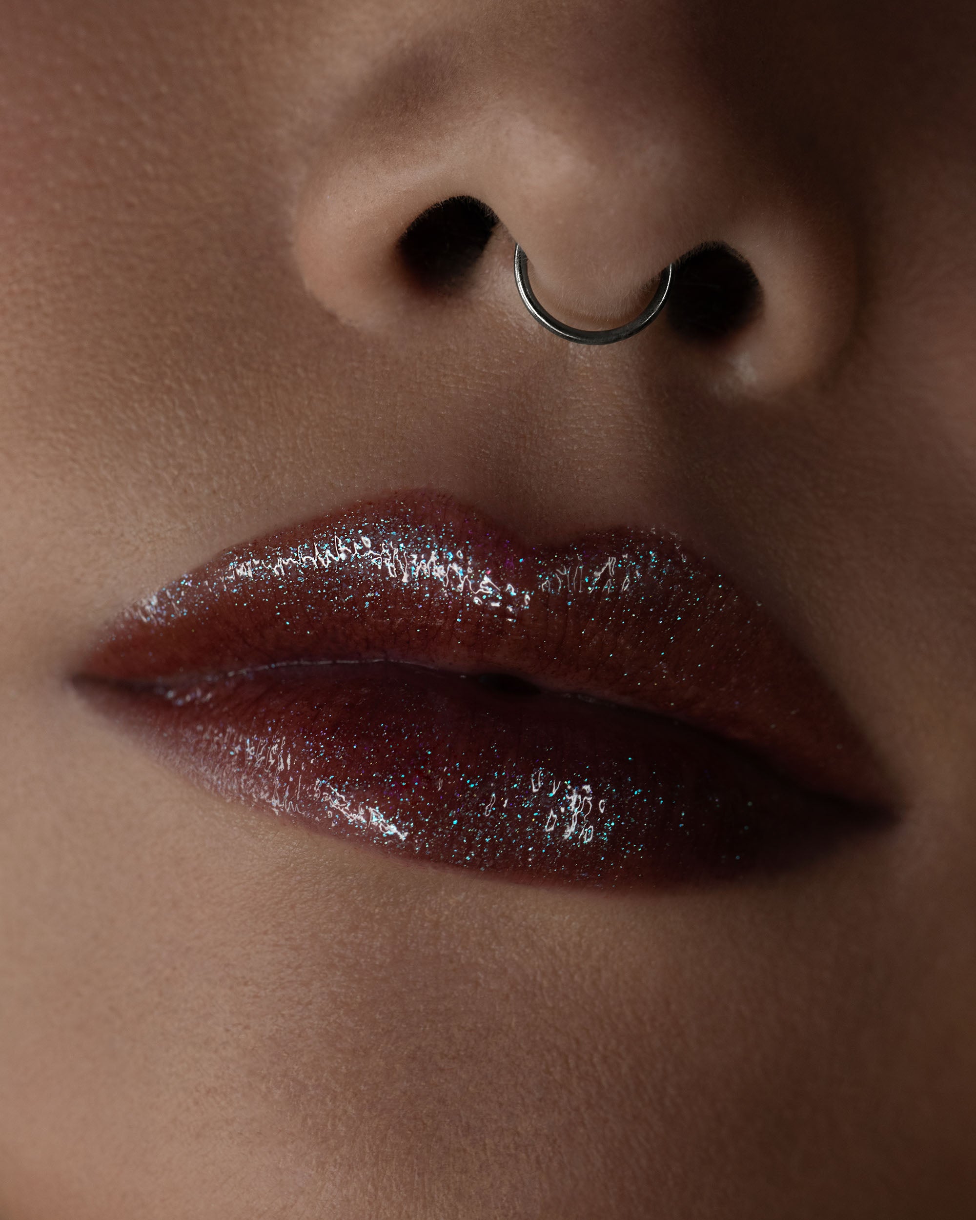 Close-up of a person's lips with a red glossy lip color and a nose ring.
