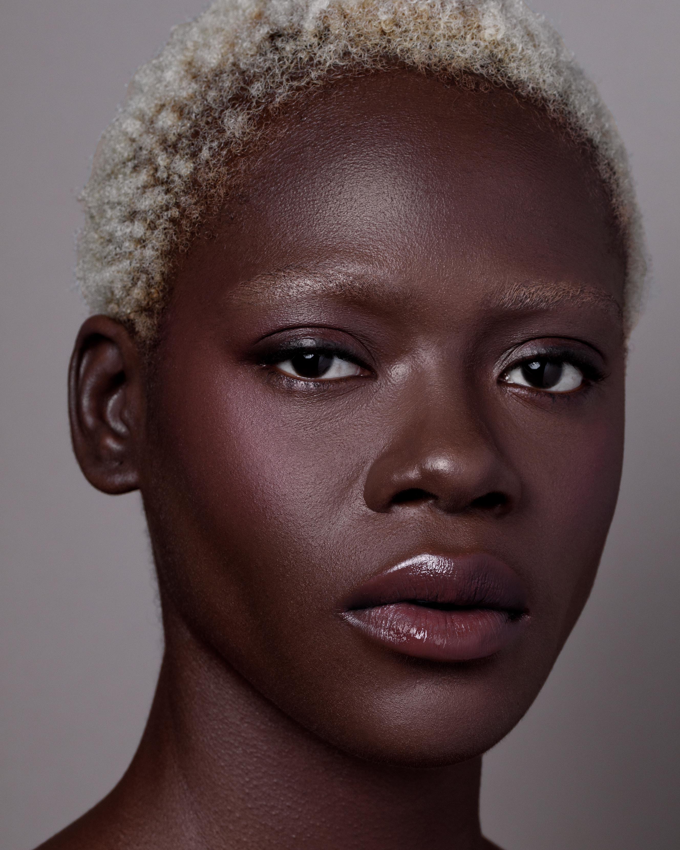 Close-up of a model with deep skin wearing nude pink makeup on lips, eyes, and cheeks