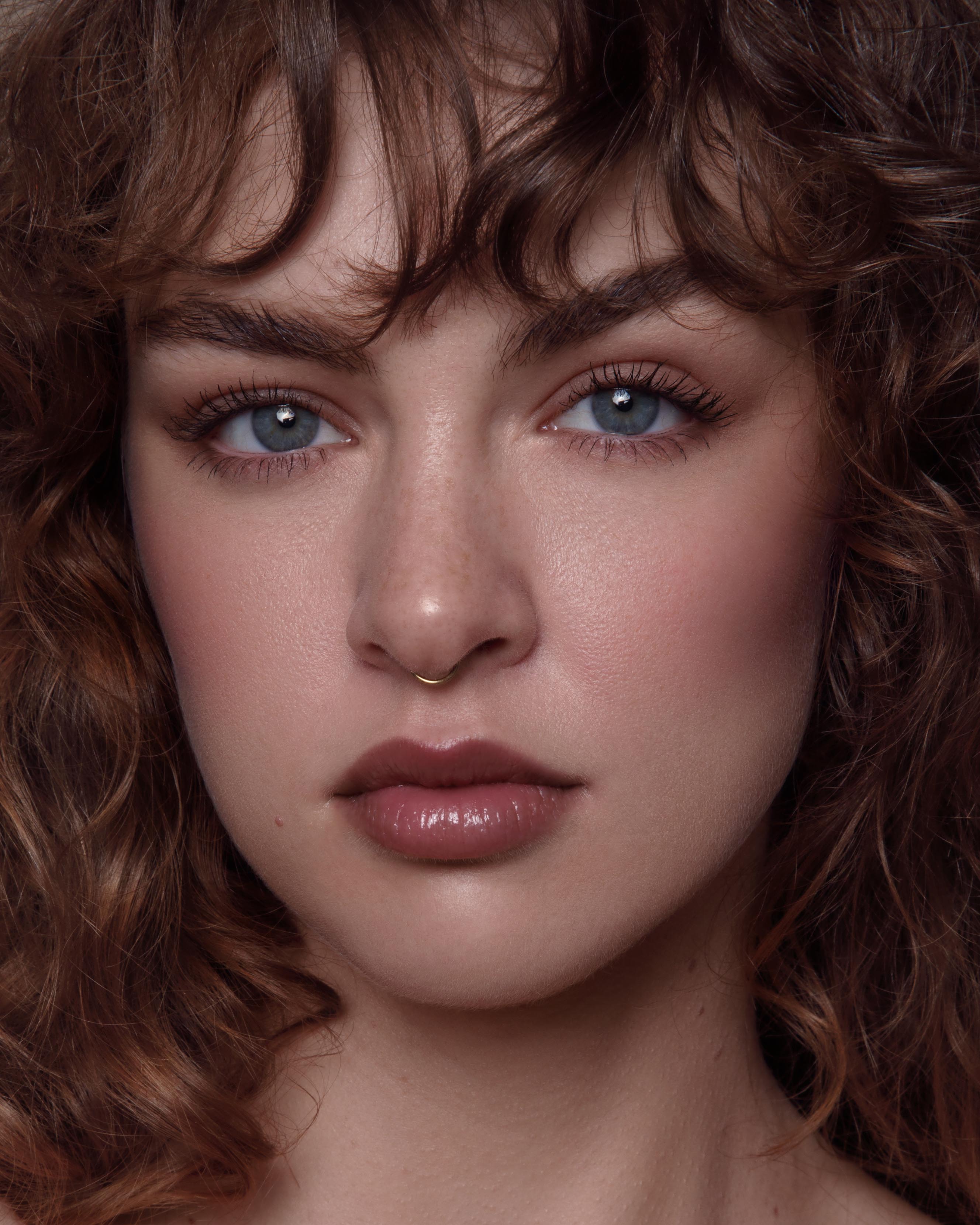 Close-up of a model with light skin wearing nude pink makeup on lips, eyes, and cheeks