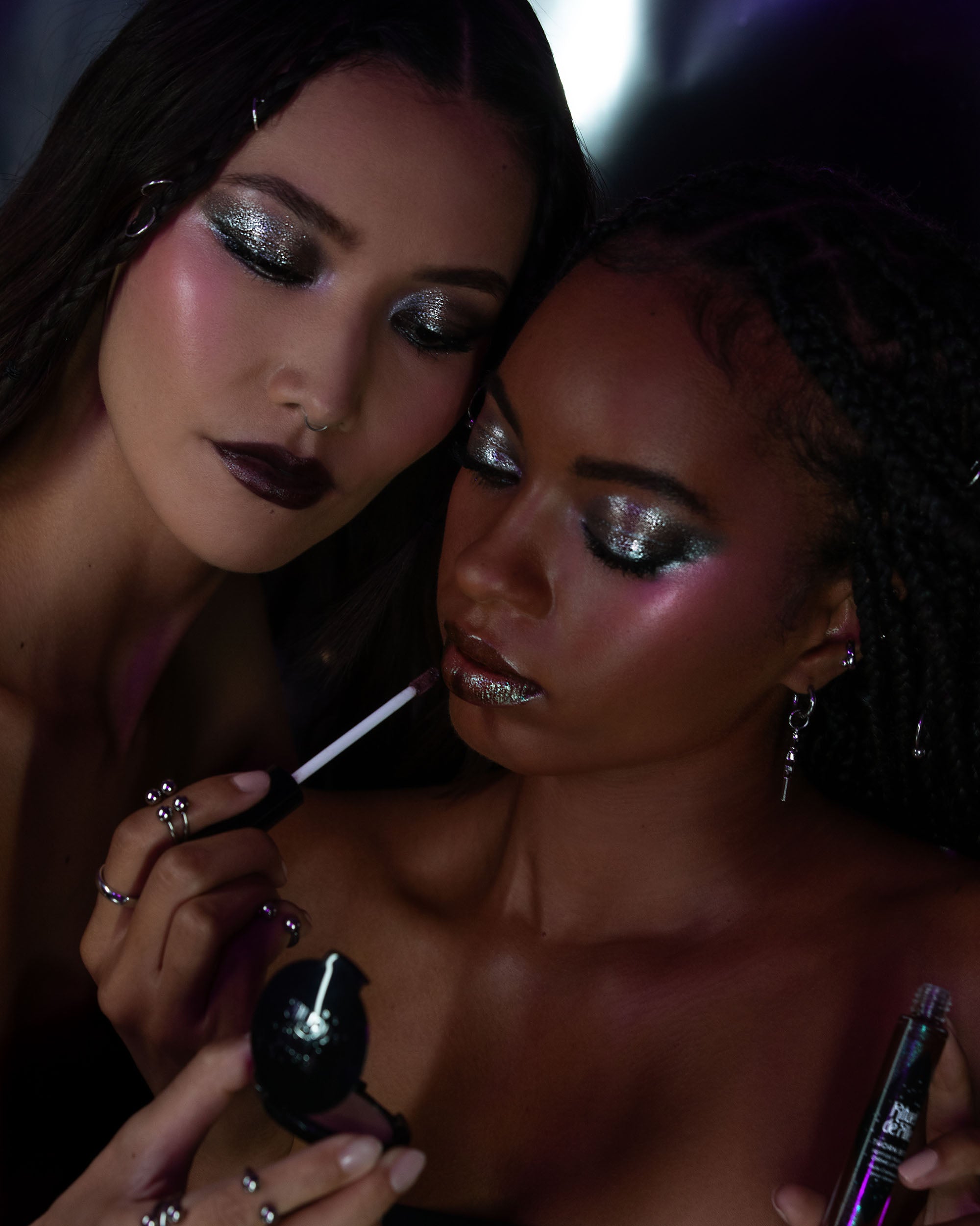 Two women applying makeup with a focus on their faces.