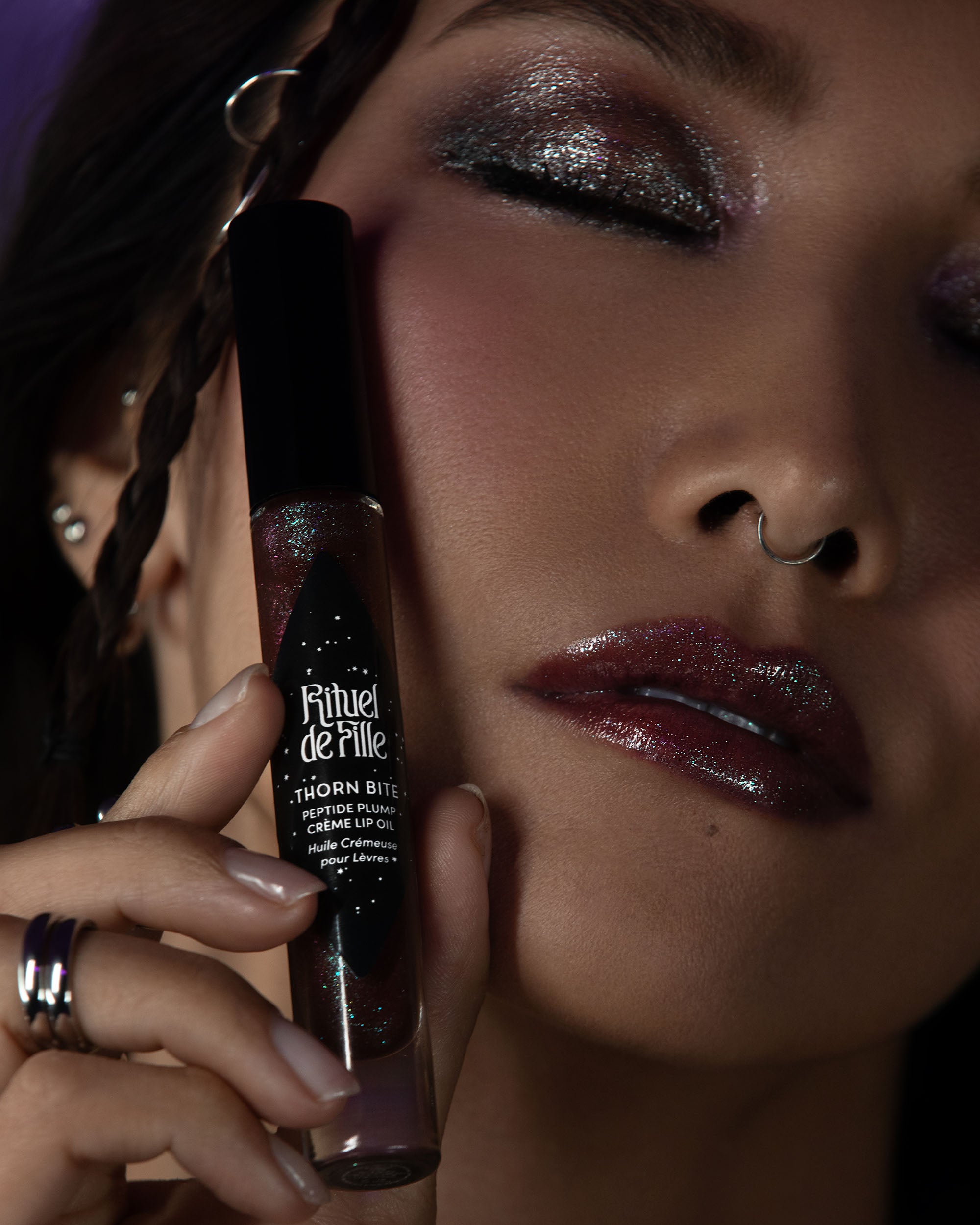 Woman holding a lip gloss with a dark background