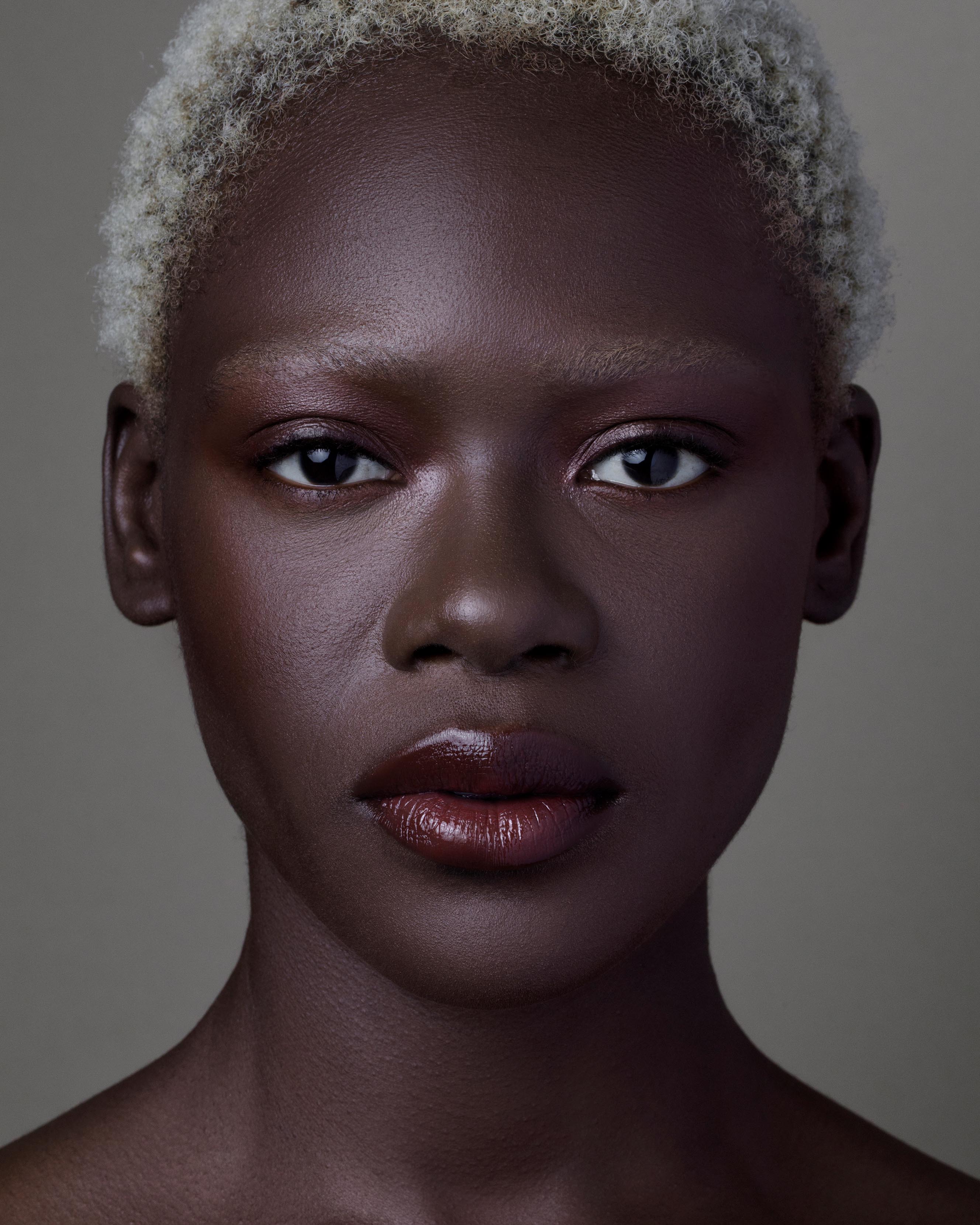 Close-up of a model with deep skin wearing burgundy red makeup on lips, eyes, and cheeks
