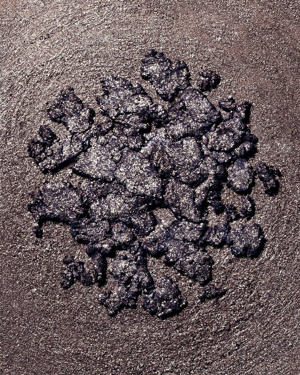 Pile of dark gray makeup on a textured brown surface