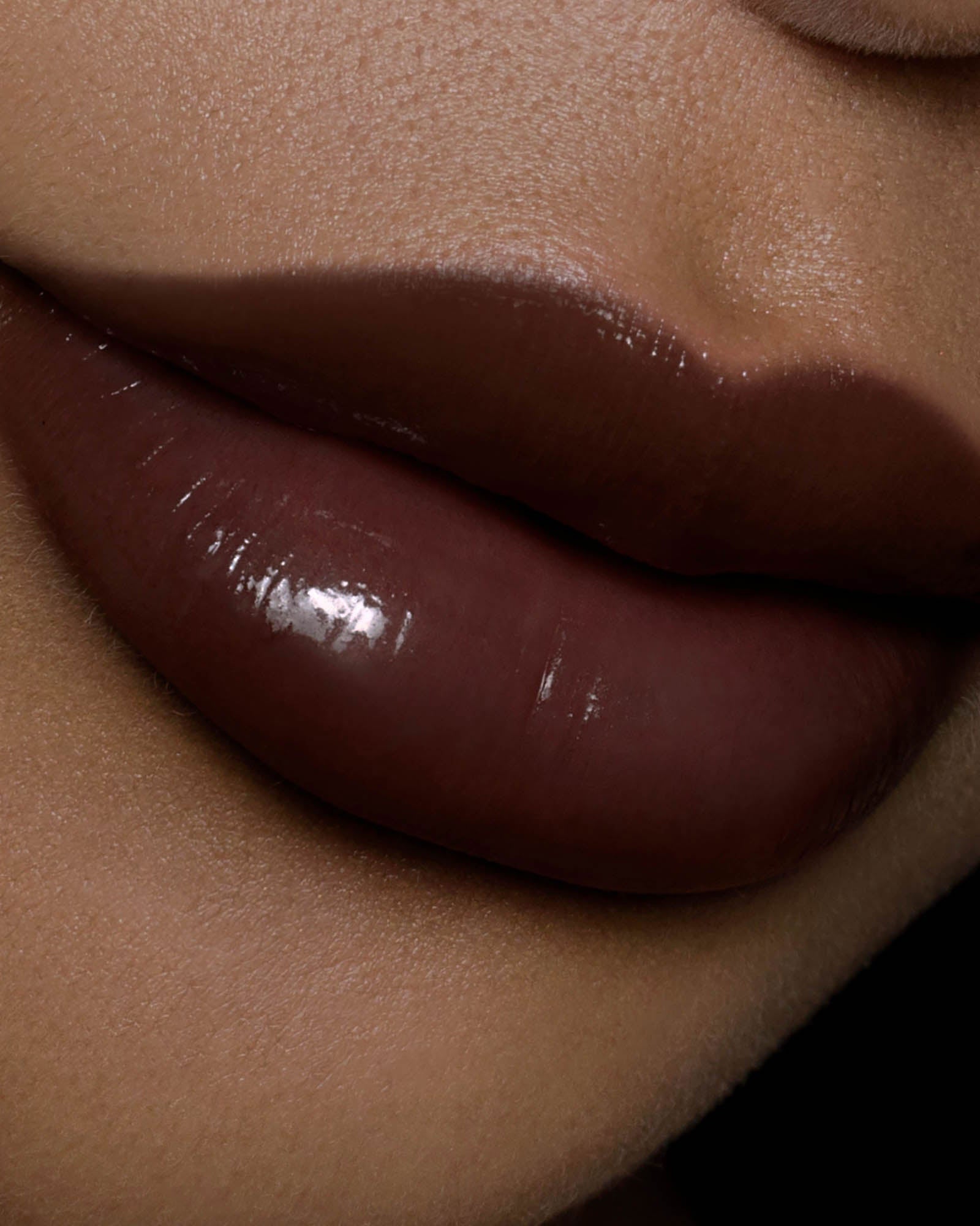 Close-up of a glossy brown lipstick on a person's lips.